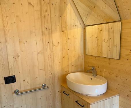 Bagno in legno con lavabo bianco e specchi angolari.
