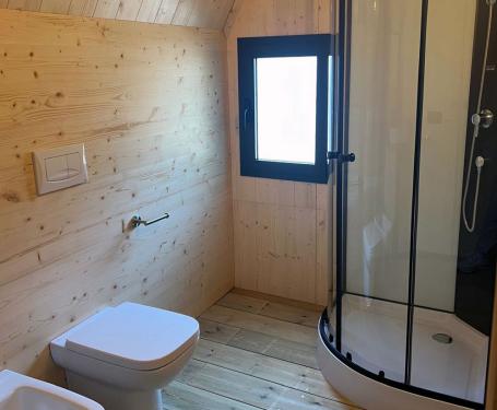 Modern bathroom with wooden panels, shower, and bidet.