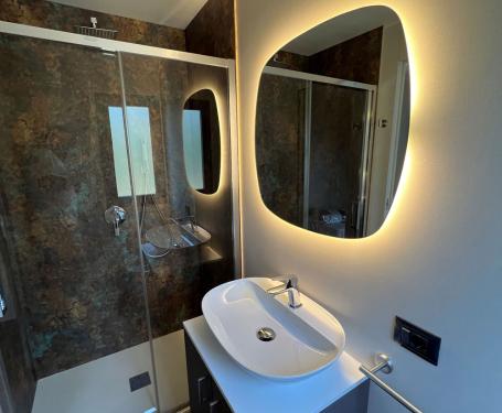 Modern bathroom with shower, sink, and illuminated mirror.