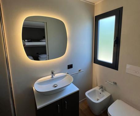 Modern bathroom with sink, bidet, and backlit mirror.
